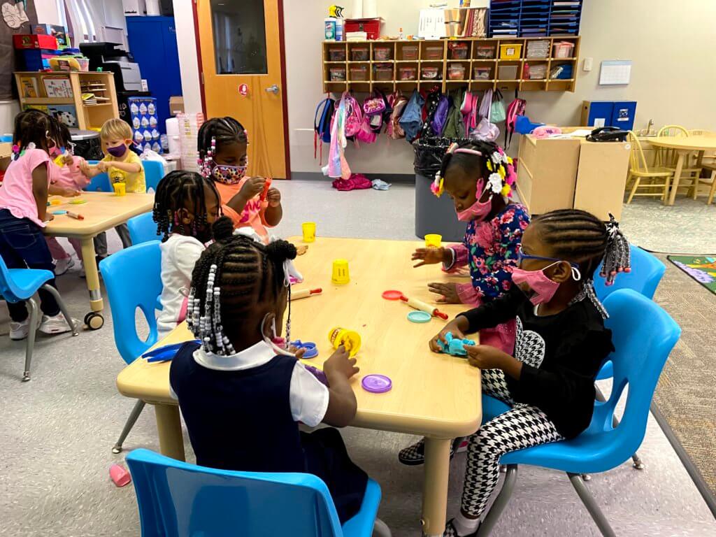 Children sitting together in the classroom, socializing and playing together.