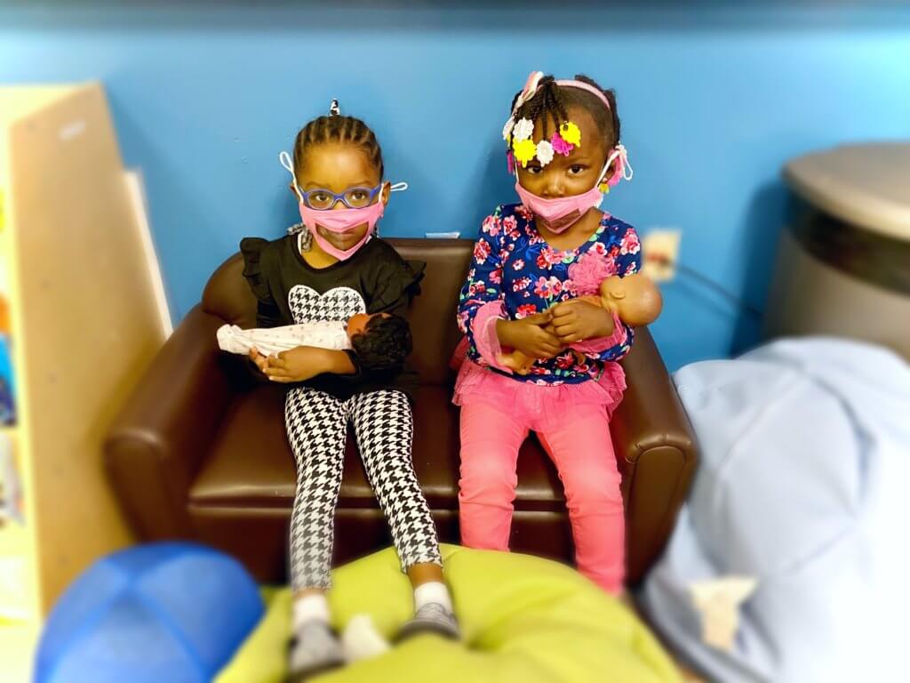 Two students sit together on a couch, each holding a toy while they play together.