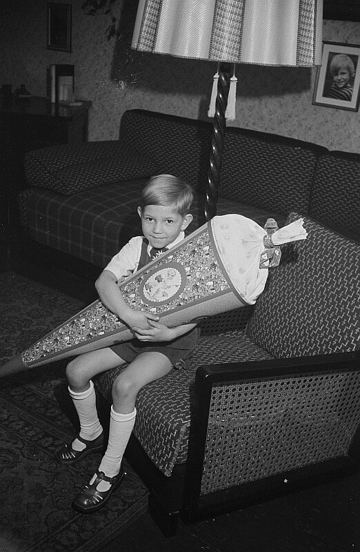 Black and white picture of a young German boy holding his schultute, or school cone on the first day of grade school.