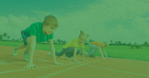 Young students smile as they line up at the starting line on the school track and field.